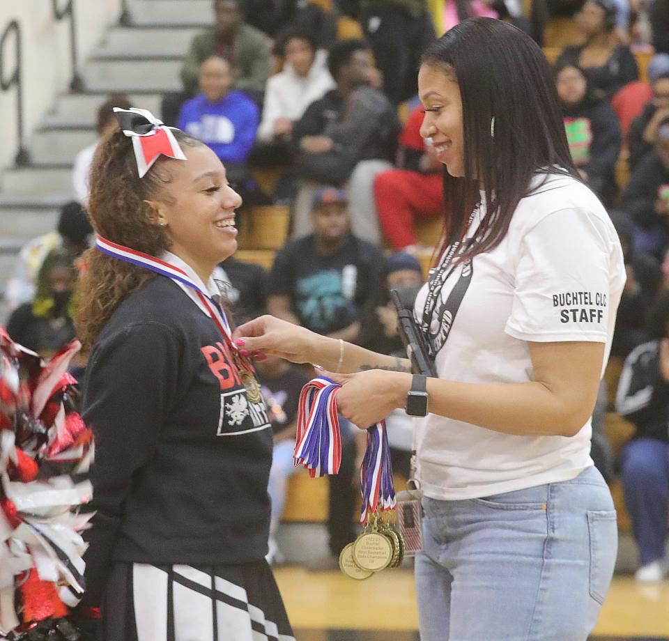 Buchtel High School cheerleader Mariyah Jones is presented a Division II state championship medal from principal LaCresia Beecher during a school assembly honoring the basketball team on Wednesday, March 22, 2023.