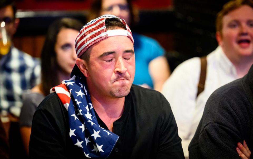 A man wearing an American flag baseball caps reacts with a grimace during the first presidential debate.