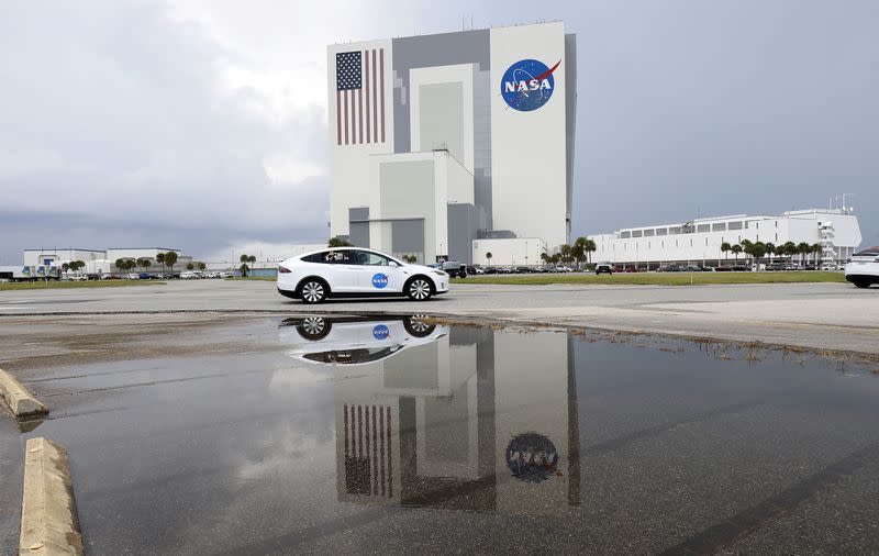 NASA astronaut Douglas Hurley waves from his Tesla as they pass the VAB heading to Pad39A for the launch of the SpaceX Crew Dragon