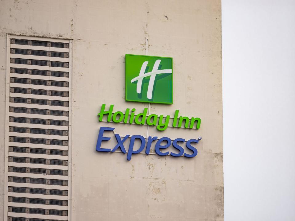 Holiday Inn Express logo sign on a weathered building facade. The hospitality company is part of the InterContinental Hotels Group business.