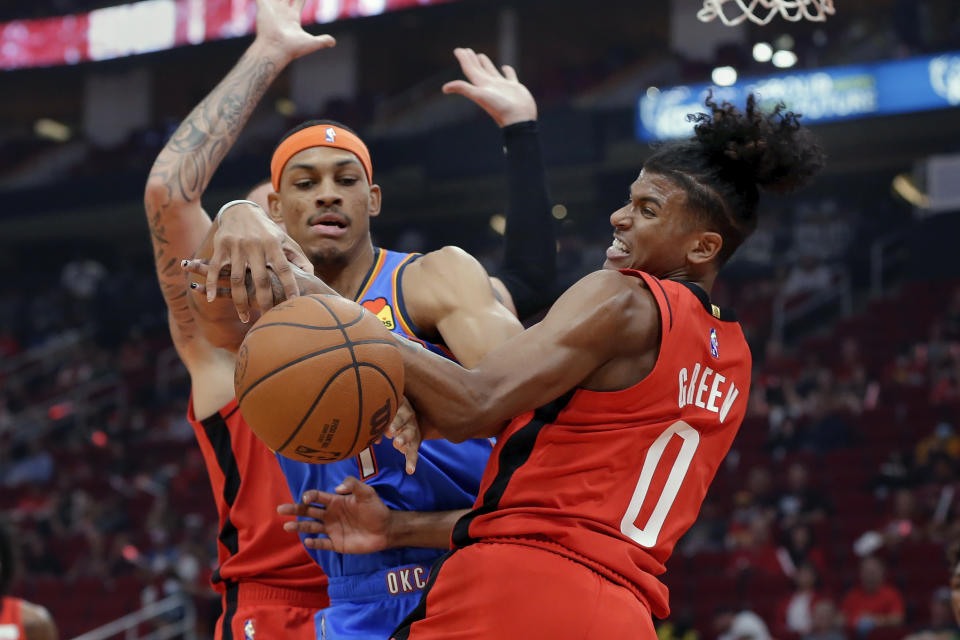 Oklahoma City Thunder forward Darius Bazley, left, and Houston Rockets guard Jalen Green (0) become entangled as they battle for a rebound during the first half of an NBA basketball game Friday, Oct. 22, 2021, in Houston. (AP Photo/Michael Wyke)