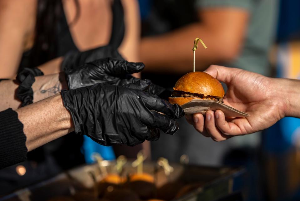An employee serves a King's Highway slider to a guest at the Inaugural Palm Springs Wine & Food Experience at Palm Springs Stadium in Palm Springs, Calif., Saturday, Nov. 19, 2022. 