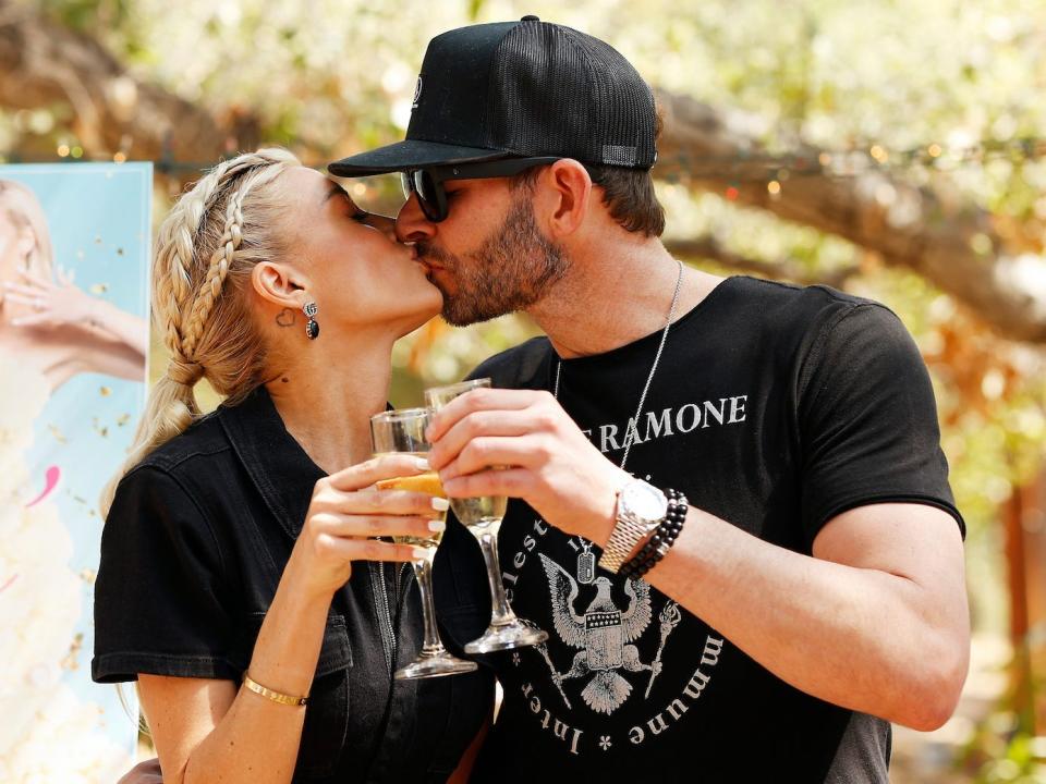 Heather and Tarek El Moussa kiss and clink champagne glasses.