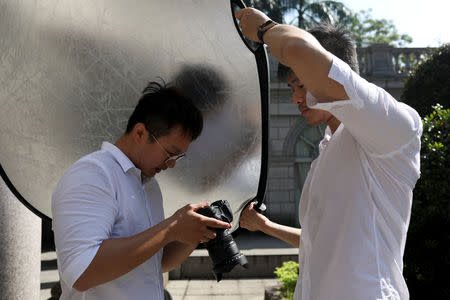 Lin Chinxuan (R), 29, holds a reflector to provide a shade for Austin Haung, 32, during a photoshoot in Taipei, Taiwan, November 11, 2018. REUTERS/Ann Wang