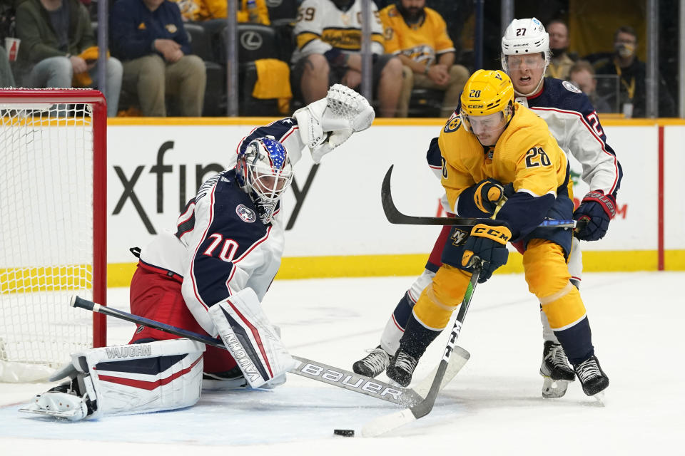 Columbus Blue Jackets goaltender Joonas Korpisalo (70) reaches to block Nashville Predators right wing Eeli Tolvanen (28) in the second period of an NHL hockey game Tuesday, Nov. 30, 2021, in Nashville, Tenn. (AP Photo/Mark Humphrey)