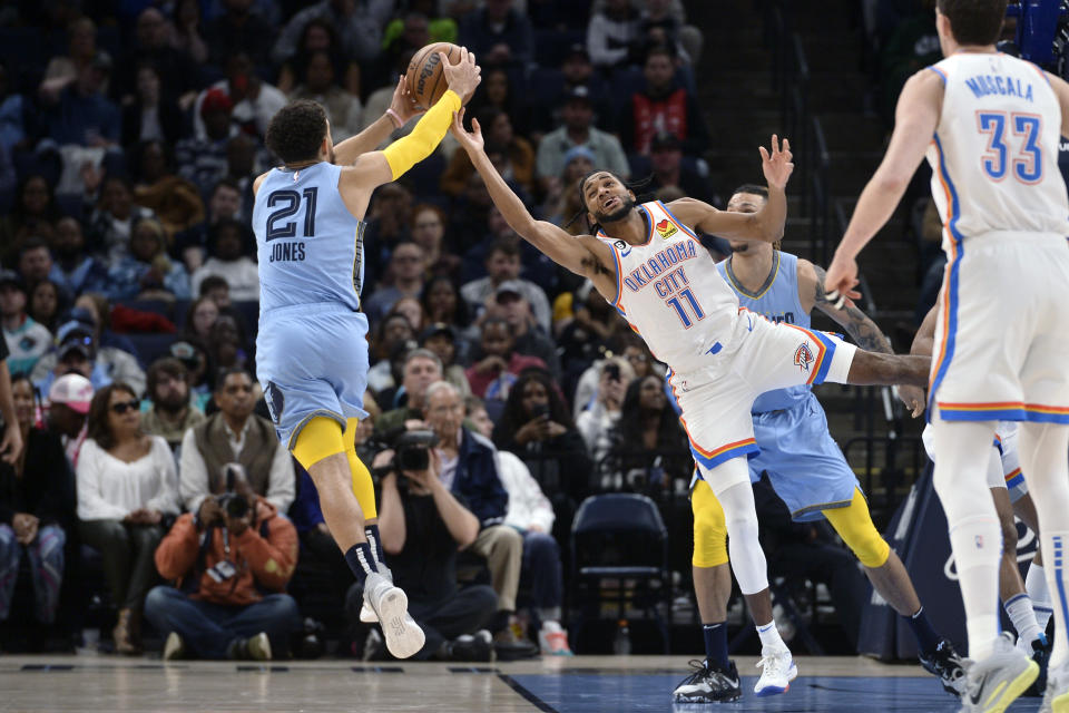 Memphis Grizzlies guard Tyus Jones (21) and Oklahoma City Thunder guard Isaiah Joe (11) reach for the ball during the second half of an NBA basketball game Wednesday, Dec. 7, 2022, in Memphis, Tenn. (AP Photo/Brandon Dill)