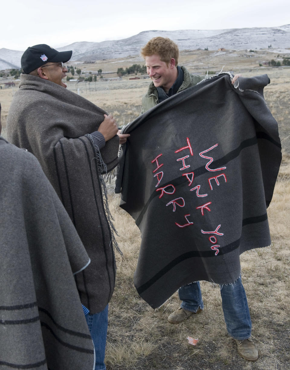 Britain's Prince Harry, right, is presented with a specially embroidered traditional blanket, by Lesotho's Prince Seeiso, before visiting a school for local herd boys opened by Sentebale, a charity for disadvantaged Lesotho youngsters, co-founded by the two Princes, in the remote village of Semongkong, Lesotho.