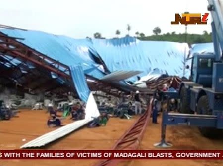 People stand near the remains of a church which collapsed during a service in the southern city of Uyo in Akwa Ibom state, Nigeria in this still image from video December 10, 2016. Video taken December 10, 2016. NTA via REUTERS TV