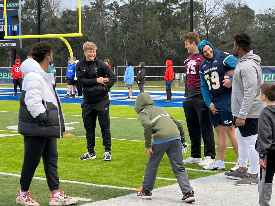 UWF quarterback Austin Reed (center, black jacket) having fun with Reese's Senior Bowl players during Thursday's youth clinic at UWF's Pen-Air Field.