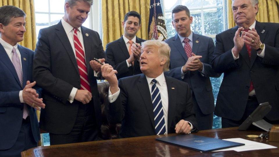 President Donald Trump hands his pen to U.S. Rep. Bill Huizenga, R-Zeeland, after signing legislation in 2017 that removed some Dodd-Frank regulations on oil and gas companies.