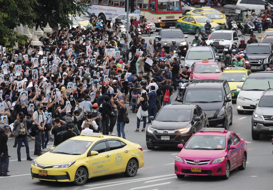 Pro-democracy demonstrators hold posters of protest leaders who have been arrested, during an anti-government protest at Victory Monument in Bangkok, Thailand, Sunday, Oct. 18, 2020. Thai police on Sunday declined to say whether they were taking a softer approach toward student anti-government demonstrations, after several mass rallies attracting thousands of protesters ended peacefully in Bangkok on Saturday. (AP Photo/Sakchai Lalit)