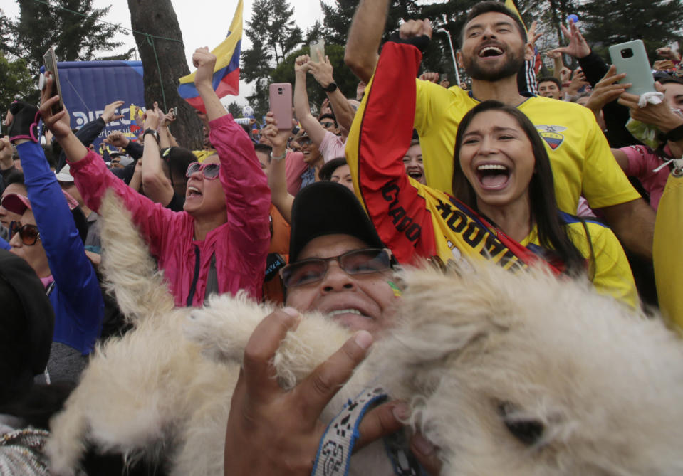 Un grupo de seguidores, incluido uno que carga en brazos a su perro, festejan luego que el ciclista ecuatoriano Richard Carapaz gana el Giro de Italia, el domingo 2 de junio de 2019. Los espectadores vieron la última etapa de la competición en una pantalla gigante, instalada en una plaza pública de Quito (AP Photo/Dolores Ochoa)