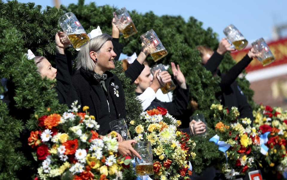 People lift glasses during a parade as part of the opening of the 186th 'Oktoberfest' beer festival in Munich, Germany, Saturday, Sept. 21, 2019. (AP Photo/Matthias Schrader)