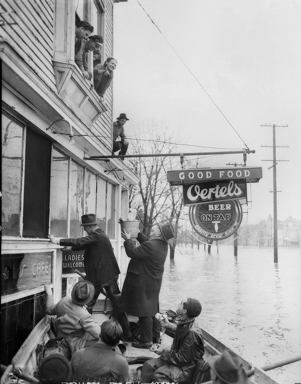 Rescuers raise a bucket with supplies to a stranded family during flooding in Louisville. By George Bailey, The Courier-Journal. 1937.