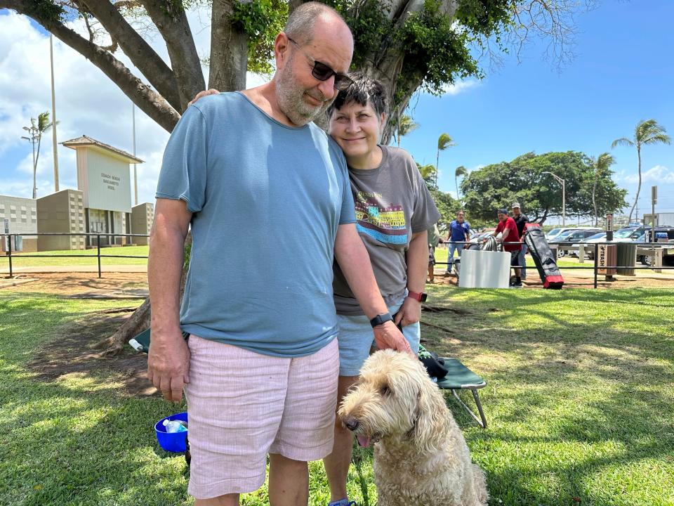 Mauro Farinelli and his wife, Judit, stand with their dog, Susi, at an evacuation shelter in Wailuku, Hawaii, on Aug. 9, 2023, after escaping fires that engulfed their town of Lahaina on the island of Maui.