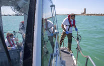 In this picture taken on Thursday, May 21, 2020, Italian Lazio region's environmental agency biologists Salvatore De Bonis, right, and Valentina Amorosi show how they perform tests on sea water during an interview with The Associated Press on a Coast Guard boat off Fiumicino, near Rome. Preliminary results from a survey of seawater quality during Italy’s coronavirus lockdown indicate a sharp reduction in pollution from human and livestock waste in the seas off Rome. Authorities stressed it was too soon to give the lockdown sole credit for the change. (AP Photo/Domenico Stinellis)