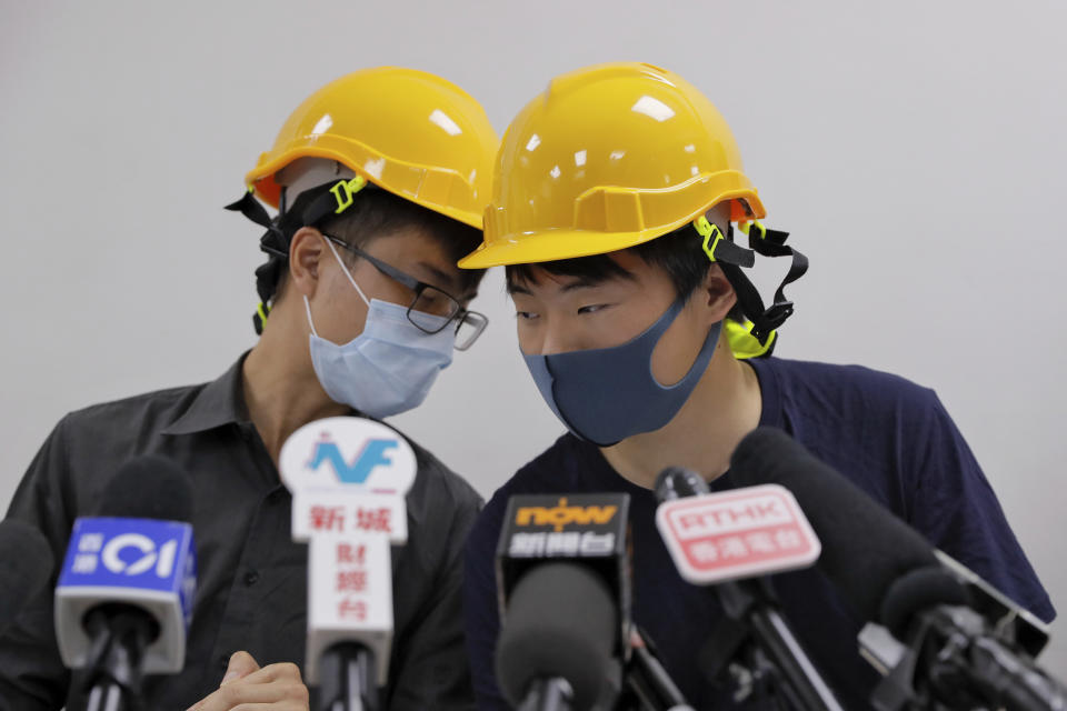 Protesters Jerry Chan, right, chats with Linus Kim during a press conference in Hong Kong, Tuesday, Aug. 6, 2019. Hong Kong protesters Tuesday condemned what they call the government's "empty rhetoric" and instances of alleged police abuse in an inaugural "People's Press Conference." (AP Photo/Kin Cheung)