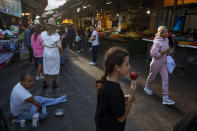 A man begs for money as others shop at Hacarmel market in Tel Aviv, Israel, Thursday, Dec. 2, 2021. Residents of Israel's seaside metropolis Tel Aviv have for years complained of how expensive it is, with living costs taking a chunk out of their paychecks. A report released Wednesday, Dec. 1, 2021, by the Economist Intelligence Unit, a research group linked to the Economist magazine, said Tel Aviv has emerged as the most expensive city to live in. (AP Photo/Oded Balilty)