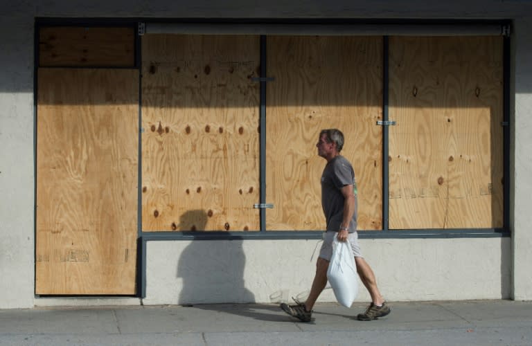 A man carries sandbags past a boarded up shop days before the arrival of hurricane Florence at Wrightsville Beach, North Carolina