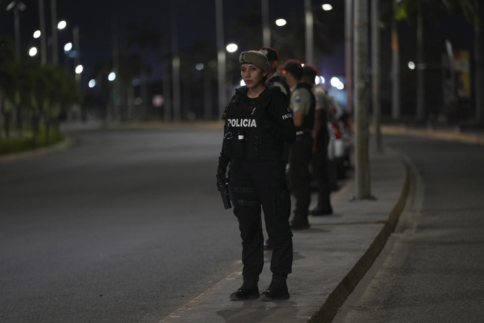 Police stand on a median during the start of a curfew decreed by Ecuador´s President Guillermo Lasso to try to reduce the ongoing wave of violence in Manta, Ecuador, Monday, July 24, 2023. (AP Photo/Dolores Ochoa)