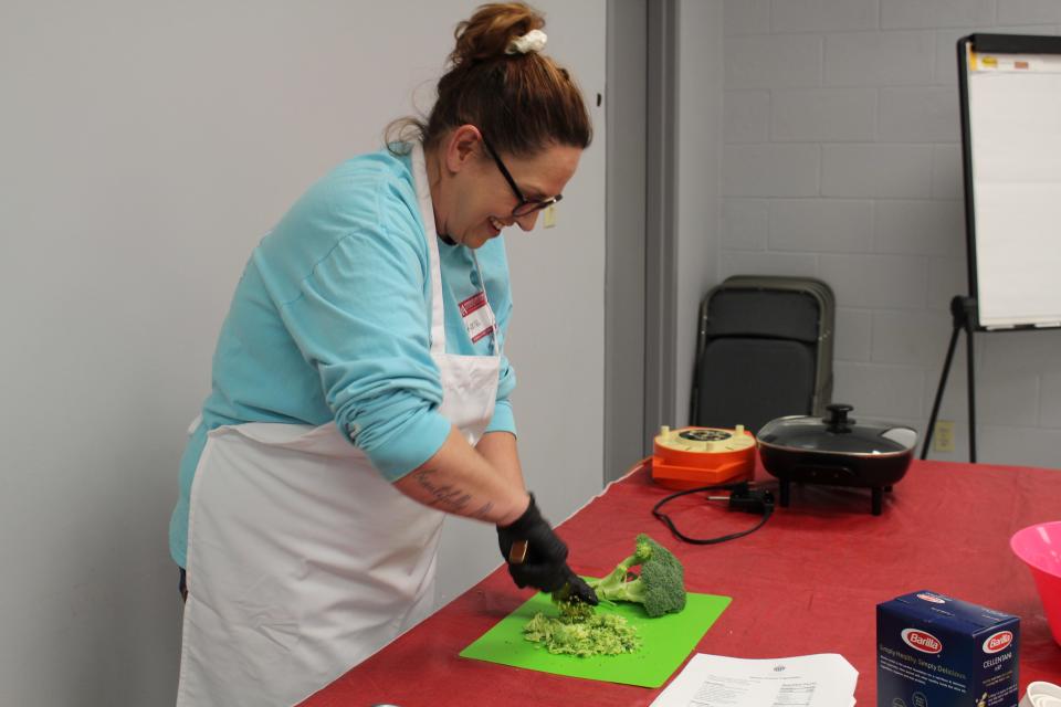 Kenna, a participant in the Cooking Arkansas class in Van Buren, cuts up broccoli for her group&#39;s winter Italian vegetable dish on March 10, 2022.