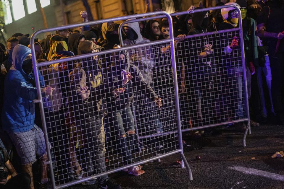 Protestors remove a fence outside the Spanish Government Office in Barcelona, Spain, Tuesday, Oct. 15, 2019. Spain's Supreme Court on Monday convicted 12 former Catalan politicians and activists for their roles in a secession bid in 2017, a ruling that immediately inflamed independence supporters in the wealthy northeastern region. (AP Photo/Bernat Armangue)