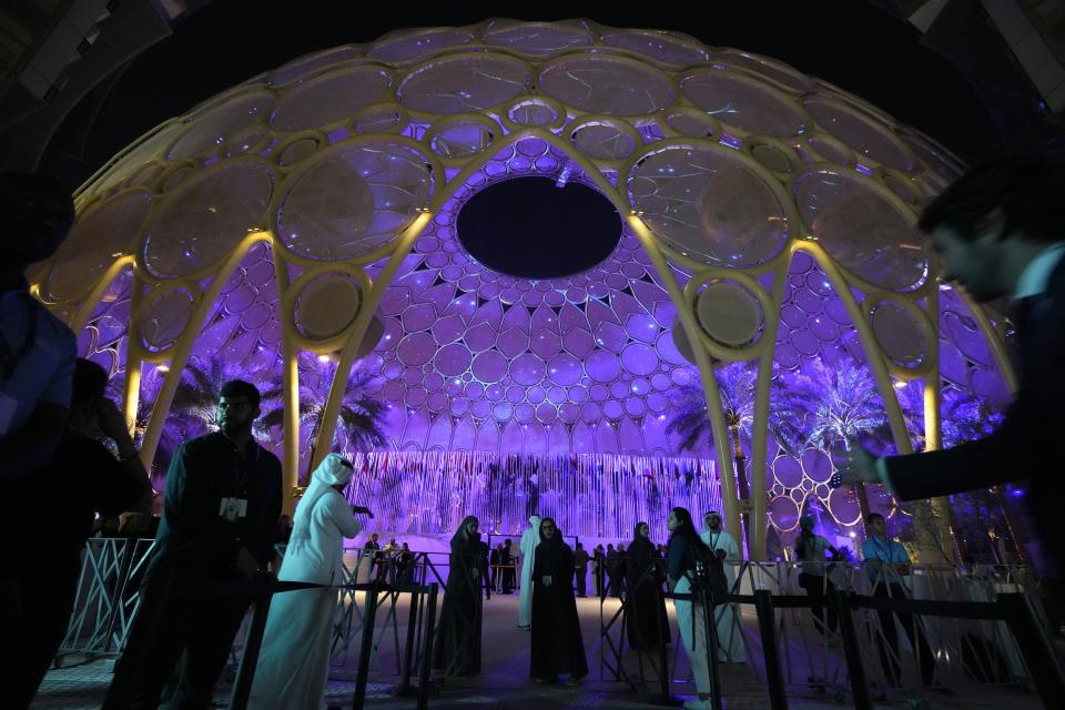 People walk near a lit up Al Wasl Dome at Expo City at the COP28 U.N. Climate Summit, Friday, Dec. 1, 2023, in Dubai, United Arab Emirates. (AP Photo/Peter Dejong)