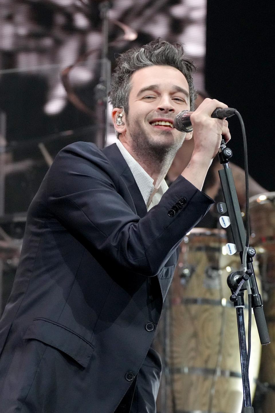 Matt Healy performing on stage in a suit