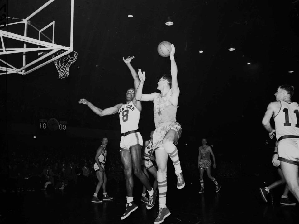 George Mikan, right, six-foot, ten-inch center for the Minneapolis Lakers, goes way up to make a goal as New York Knickerbockers' six-foot, seven-inch center Nat "Sweetwater" Clifton  (8) makes an unsuccessful attempt to defend on April 8, 1953 at the 69th Regiment Armory in New York.  (AP Photo)