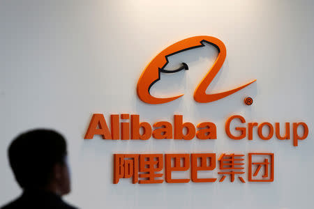 FILE PHOTO: A man stands near the logo of Alibaba Group at the company's newly-launched office in Kuala Lumpur, Malaysia June 18, 2018. REUTERS/Lai Seng Sin/File Photo