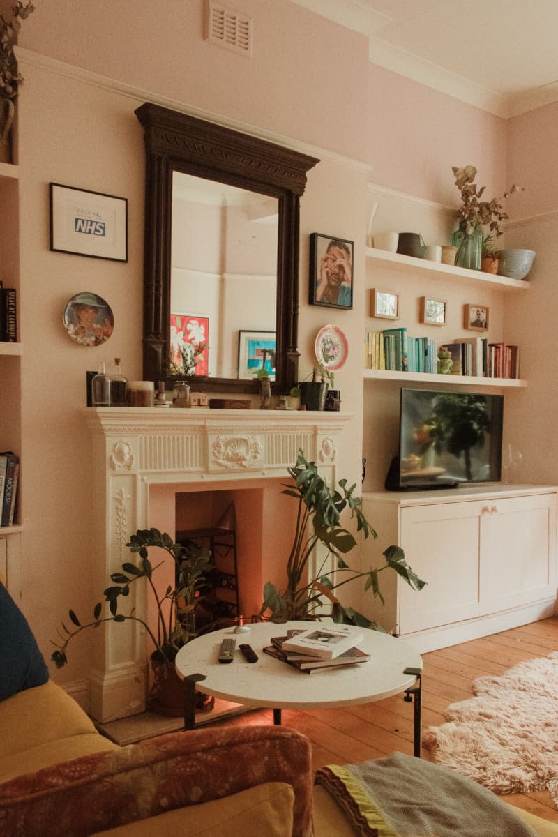 The living room has a white fireplace below a large wooden mirror.