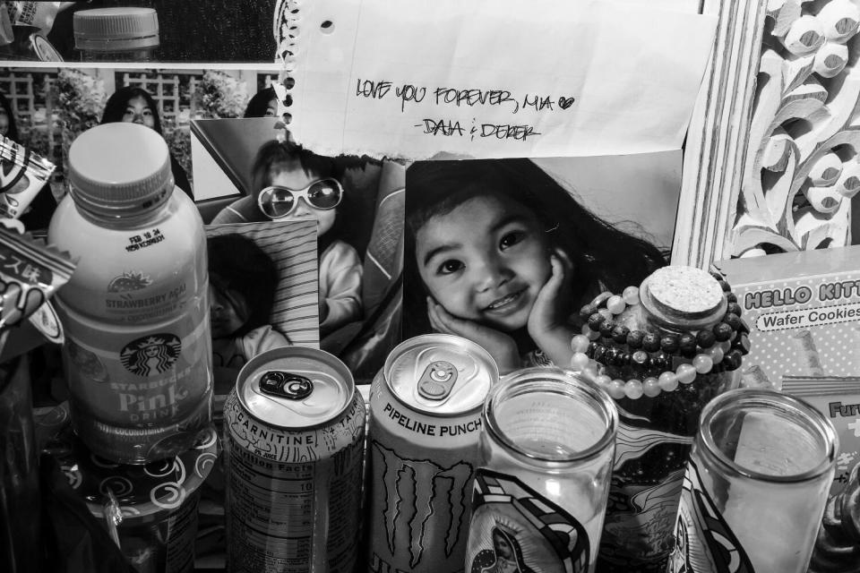 Photos of a girl are placed next to candles and cans.