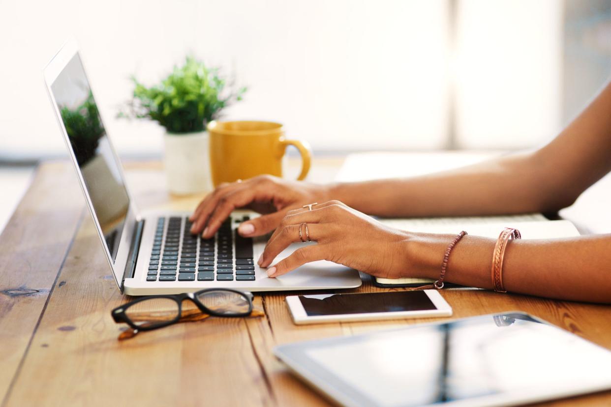 Cropped shot of an unrecognizable businesswoman sitting alone and typing on her laptop during the day at home