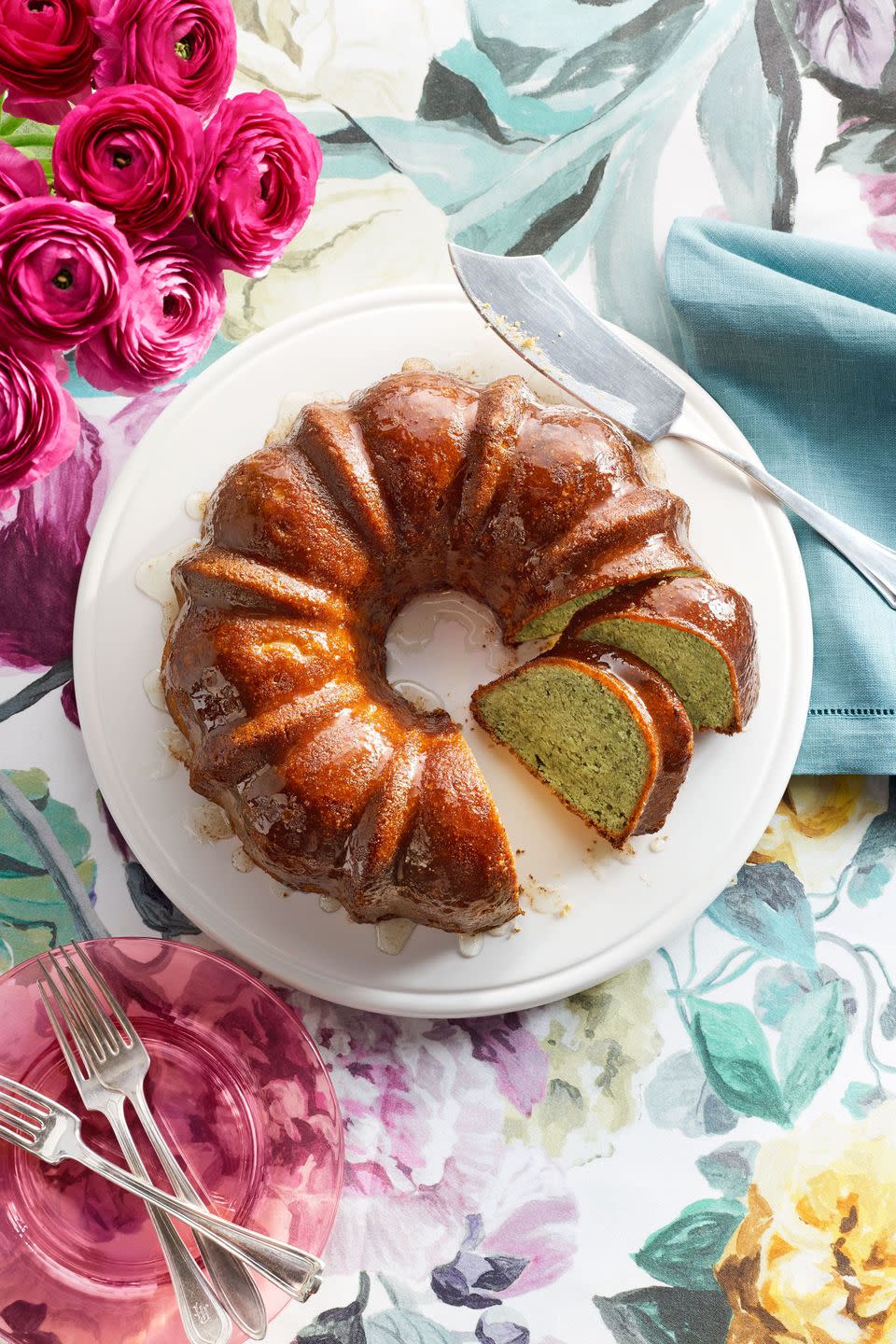 pistachio lemon bundt cake on a white cake plate with a cake server