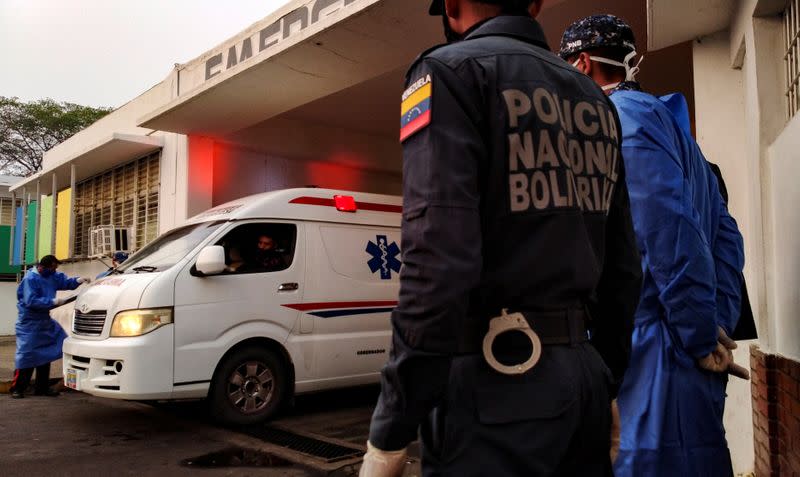 Healthcare workers and members of the Bolivarian national police watch as an ambulance arrives with prisoners outside a hospital after a riot erupted inside a prison in Guanare