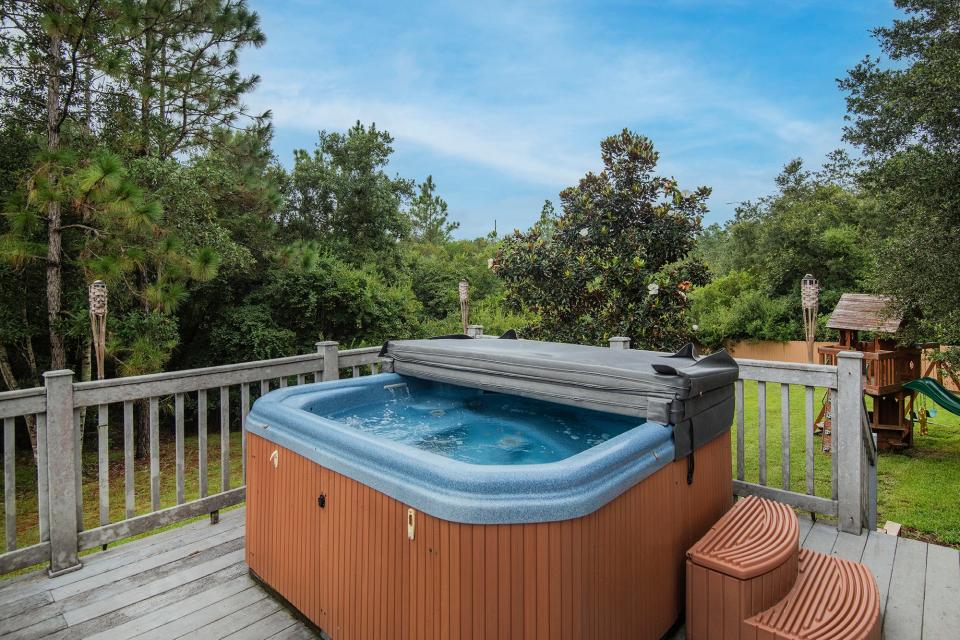 A hot tub on the deck overlooks the HOA protected green space behind the home.