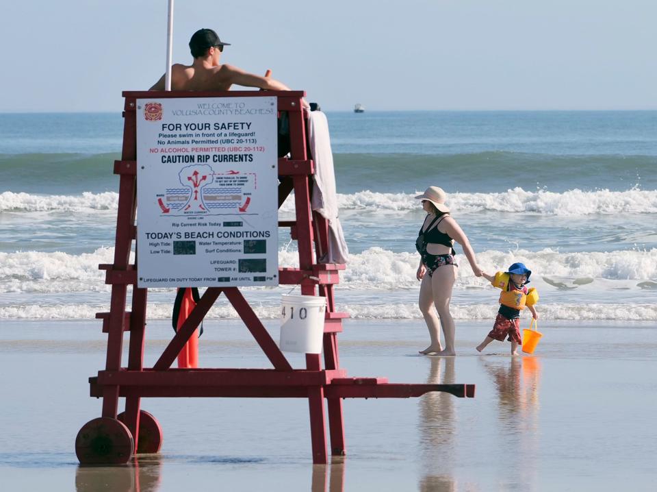 Beachgoers wade in the surf along New Smyrna Beach earlier this year. When you're out in the sun, it's important to take precautions to prevent skin damage and skin cancer, dermotologists say.