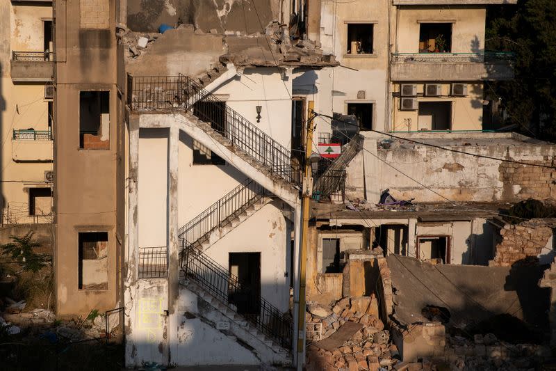 Una bandera libanesa cuelga frente a los edificios dañados por una explosión en el puerto de Beirut, en el barrio de Karantina, Líbano