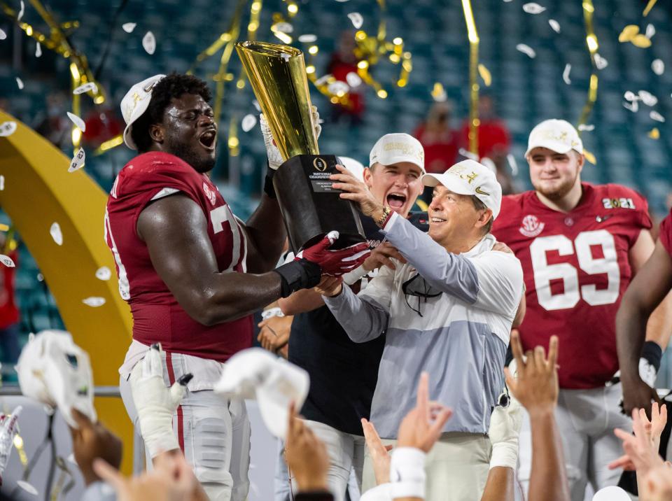 Alabama coach Nick Saban and offensive lineman Alex Leatherwood celebrated with the National Championship trophy after beating Ohio State in the 2021 CFP National Championship game.