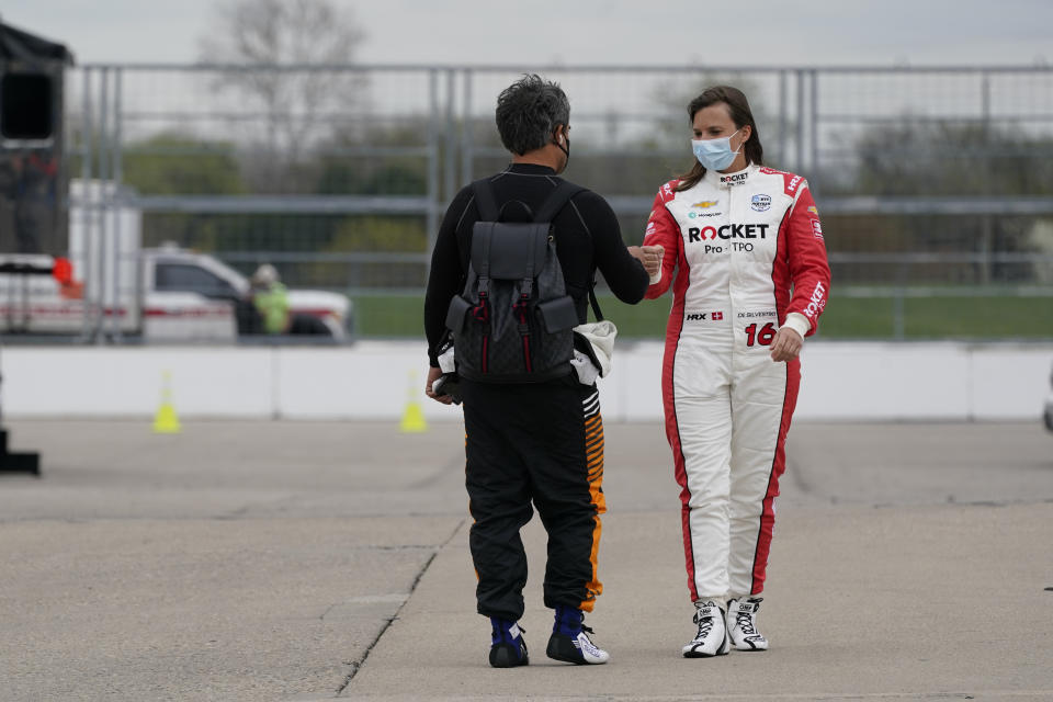 Juan Pablo Montoya, of Colombia, fist bumps Simona De Silvestro, of Switzerland, during testing at the Indianapolis Motor Speedway, Thursday, April 8, 2021, in Indianapolis. (AP Photo/Darron Cummings)