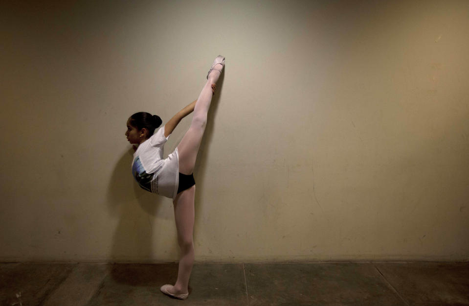 In this Sept. 3, 2012 photo, a young ballet dancer warms-up before performing in a competition between ballet schools at the National Museum in Lima, Peru. Nearly 100 girls and boys from Colombia, Venezuela, Chile, France and Peru are submitting themselves to a week-long competition hoping to win medals from Peru's national ballet school _ and perhaps a grant to study in Miami. (AP Photo/Martin Mejia)