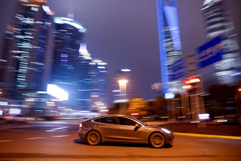 FILE PHOTO: A Tesla electric car drives past a crossing in Shanghai