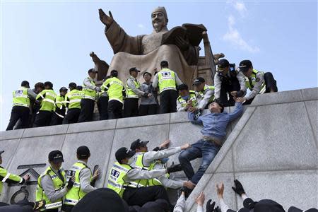 Policemen detain university students on a statue of King Sejong the Great during a protest against South Korean President Park Geun-hye, in central Seoul May 8, 2014. REUTERS/Han Jae-ho