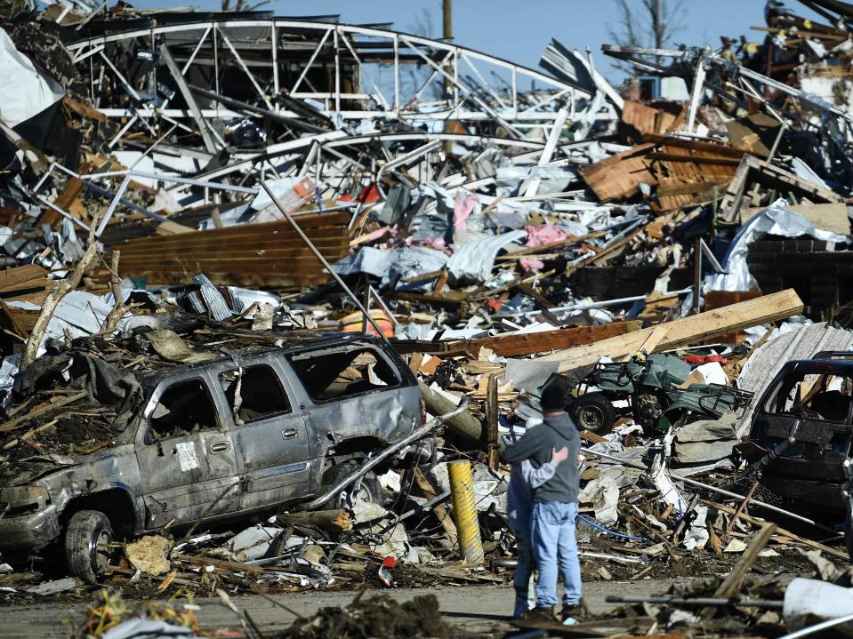 People embrace as tornado damage is seen after extreme weather hit the region December 12, 2021, in Mayfield, Kentucky (AFP via Getty Images)