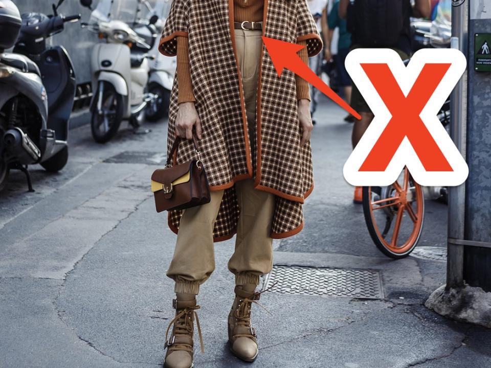 red x and arrow pointing at person posing on street in high waited brown pants and a plaid sweater