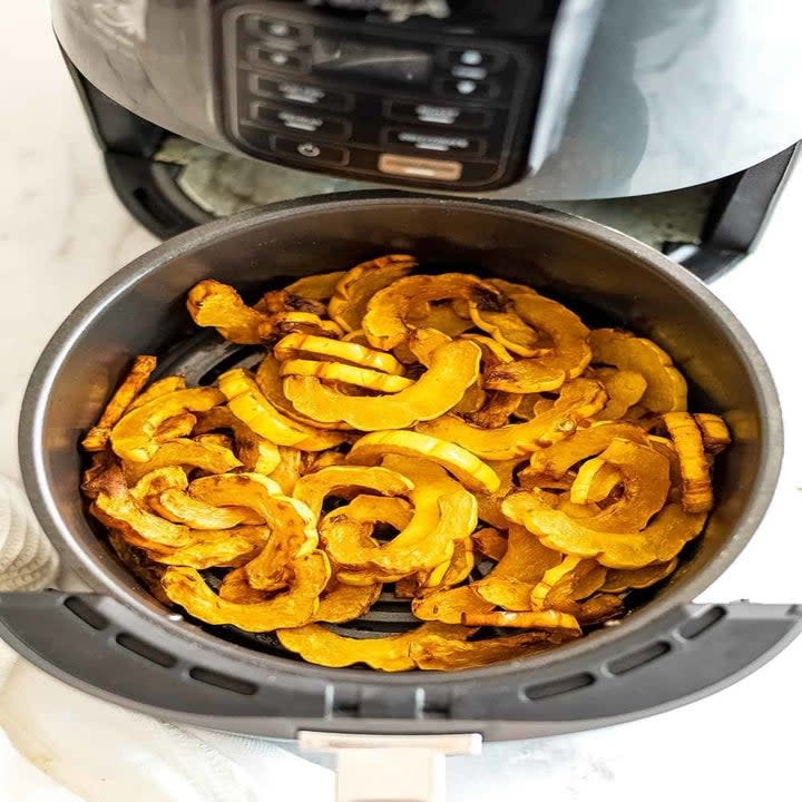 Sliced delicata squash in the basket of an air fyrer.