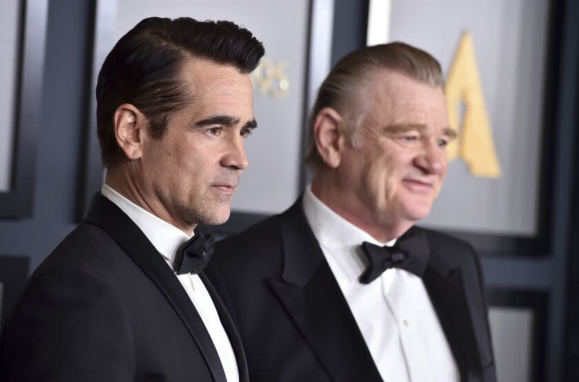 A man with short black hair and a man with short blond hair posing in matching black tuxedos and bowties