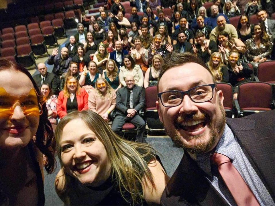 A large group of people in cocktail attire sit in a high school auditorium. (Courtesy of Josh Ryder)