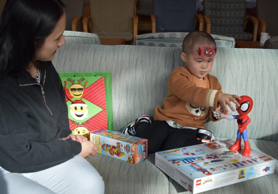 Kim Vo of Australia watches her 3-year-old son Chase enjoy Christmas presents he received from "Santa" Joe McGee at the UF Health Proton Therapy Institute in Jacksonville. Chase is being treated there for an eye tumor.