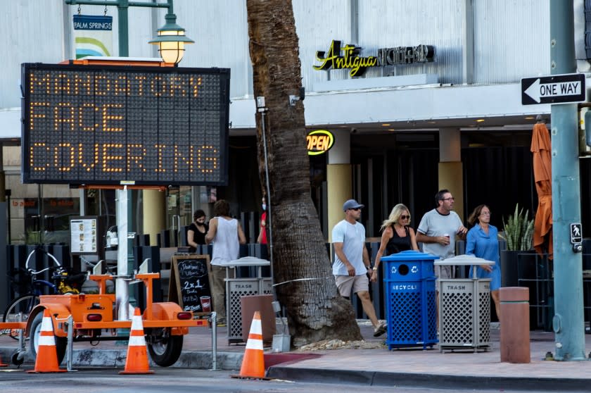 PALM SPRINGS, CA - JULY 16, 2020: Pedestrians ignore the mandatory face coverings order while walking in downtown Palm Springs on July 16, 2020 in Riverside County, California. Riverside County is experiencing a surge in COVID-19 cases.(Gina Ferazzi / Los Angeles Times)